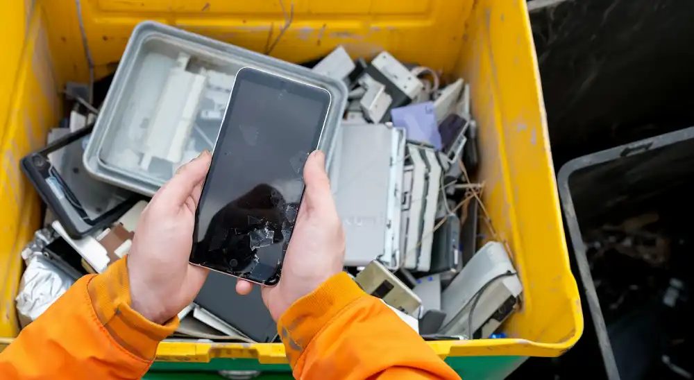 une personne dépose un téléphone portable usagé dans un bac de recyclage